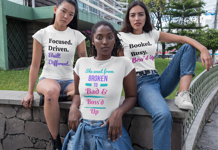 Woman wearing a black 'She Went From Broken to Bad & Boss'd Up' graphic t-shirt, walking confidently in a city hallway.